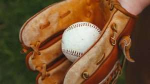 Small brown baseball glove holding a baseball.