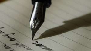 Someone uses a fountain pen to write in a journal.