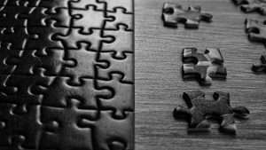 A black and white close-up image of a puzzle with a few loose puzzle pieces next to it.