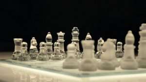A chessboard with transparent and frosted glass playing pieces.