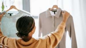 A person holds up two different shirts, trying to decide on one.