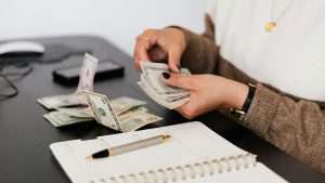 A person counting money of verious denominations.
